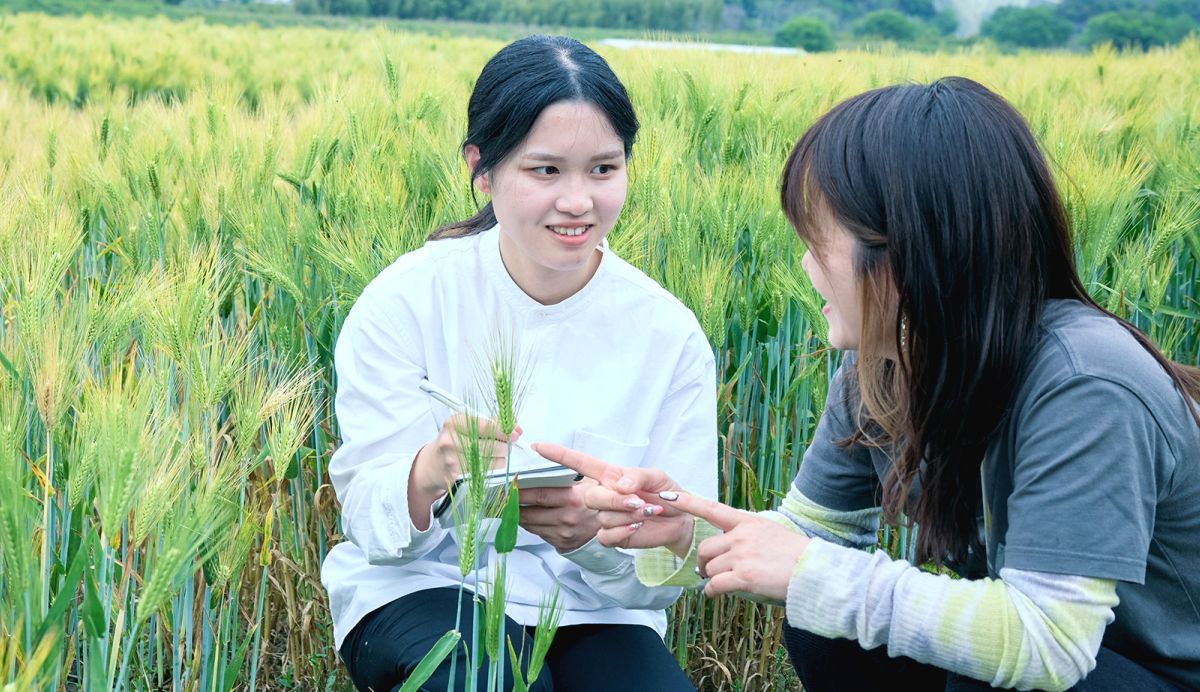 植物の前にしゃがんでお話をしている二人の女性。右側の女性は植物を指差しお話をし、もう一人の女性はメモを取っている