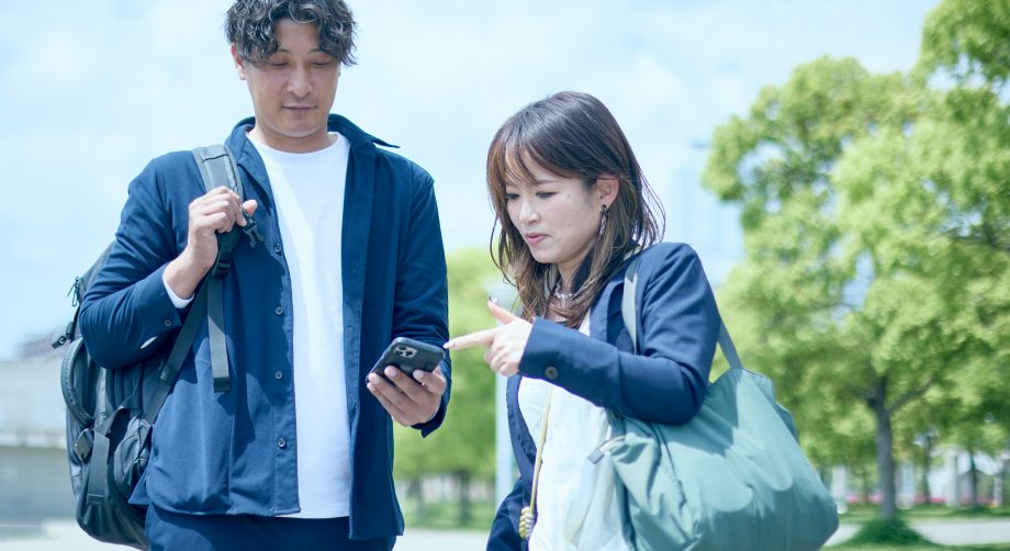 スマホを手の前に出している男性と、そのスマホを指差し見ている女性