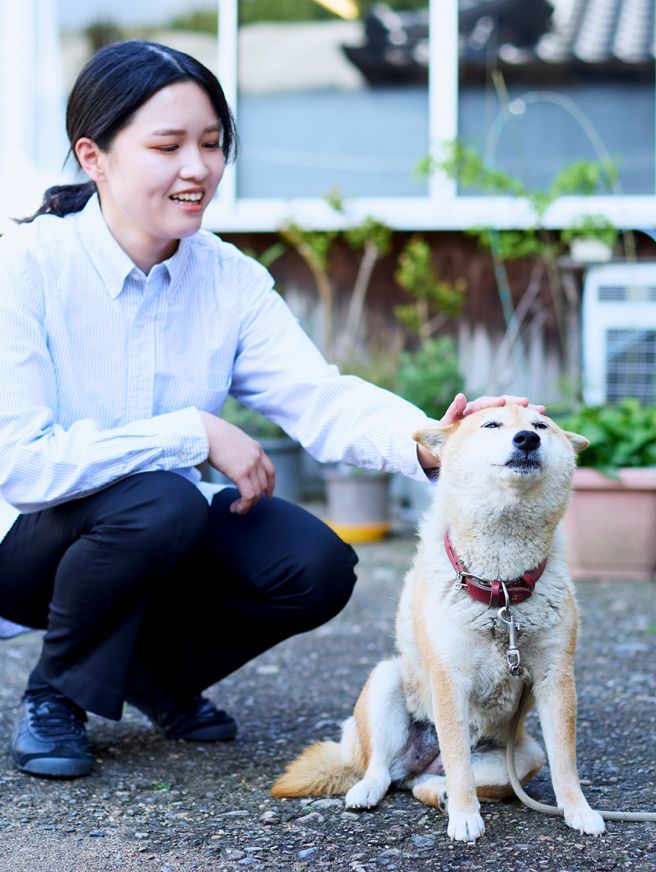 道にしゃがみ込んでワンちゃんを撫でている女性