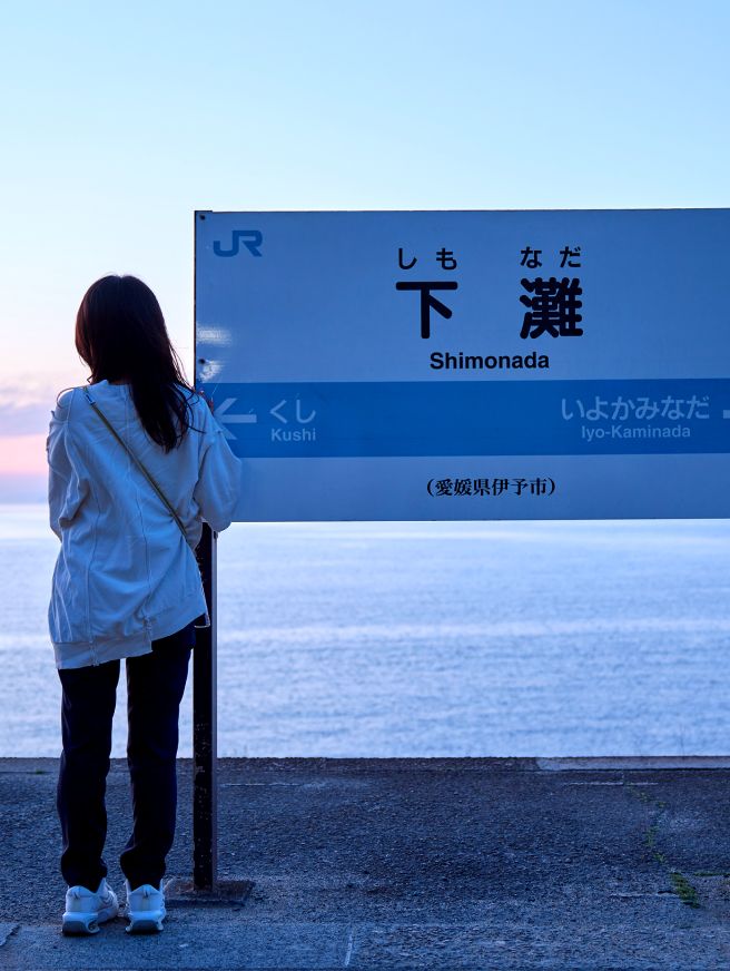 JR下灘駅のホームで海を見ている女性